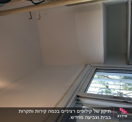 קיר צבוע בלבן ליד חלון עם צינור תקרה